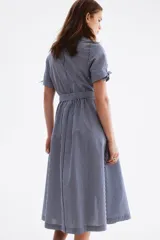 Vestido midi camisero con estampado de rayas verticales en tonos azul y blanco, cuello camisero, botonadura frontal y mangas cortas. Incluye un cinturón para anudar en la cintura y falda de corte acampanado.