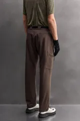 Pantalón de hombre color marrón oscuro, corte regular fit, confeccionado en tejido técnico compacto elástico. Presenta cintura ajustable con cinturón negro a contraste, bolsillos frontales, bolsillo trasero con cierre y bolsillo cargo con cierre en la pernera.