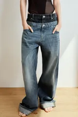 Jeans de tiro bajo confeccionados en denim, con diseño holgado y bajo con vuelta. Presentan el detalle de doble cinturilla en tonos contrastantes de azul, cierre frontal con cremallera y botón metálico, y cinco bolsillos clásicos.