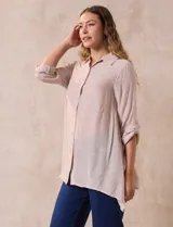 Camisa larga de rayón con cuello solapa y cierre frontal de botones. Presenta mangas con presilla para regular el largo y aberturas laterales en el ruedo.