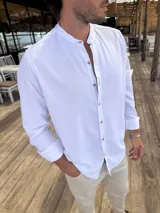 Camisa de manga larga con cuello mao y cierre frontal de botones. Confeccionada en tejido de aspecto natural, presenta un corte clásico y versátil.