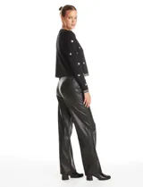Chaqueta tejida de punto color negro, con cuello redondo y cierre frontal invisible. Presenta un diseño decorado con apliques de strass facetados y perlas en forma de flores y líneas en los bordes.