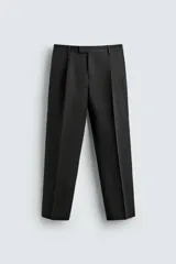 Pantalón de vestir regular fit confeccionado en lino, con pliegues frontales, bolsillos laterales y bolsillos traseros de doble vivo con botón. Presenta cierre frontal con cremallera y gancho metálico oculto.