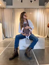 Botas altas de cuero marrón con suela track y tres tiras con hebillas metálicas en la caña.