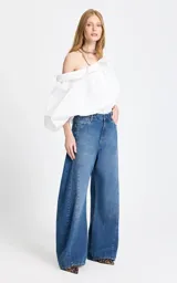 Jean de tiro alto con corte wide leg, confeccionado en denim azul clásico. Presenta costuras verticales frontales que estilizan la silueta y un diseño de pierna ancha.