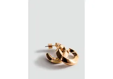 Aros de metal dorado con diseño de argollas gruesas de formas geométricas torsionadas.