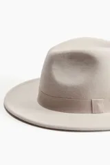 Sombrero tipo fedora color beige, de fieltro, con cinta de grosgrain alrededor de la copa.