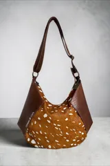 Cartera bandolera de cuero marrón con detalles en cuero con pelo con estampado animal print. Cuenta con diseño geométrico, correa ajustable y cierre superior.