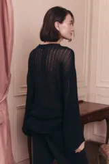Sweater de punto calado color negro, con escote redondo y mangas largas. Presenta un diseño de tejido abierto y holgado.