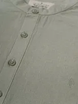 Camisa de lino color crudo, de manga larga con puños abotonados y cuello mao.