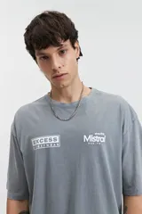 Remera de corte oversize color gris azulado con cuello redondo y mangas cortas. Presenta estampados en blanco en el pecho con los logotipos de Excess Streetwear y Mistral.