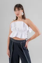 Top strapless blanco con diseño estructurado y volados en la parte inferior. Presenta una cintura elástica fruncida y un detalle de lazo lateral.