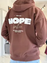 Canguro oversize marrón chocolate con capucha, bolsillos laterales y estampa en la espalda con la leyenda "Keep your HOPE alive".