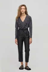 Pantalón sastrero negro de tiro alto con silueta tipo carrot. Tiene cintura ceñida con pliegues en el frente, bolsillos laterales y un bolsillo de ojal en la parte trasera. Confeccionado con taffeta.