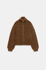 Chaqueta de punto de textura suave en color marrón, con cuello alto, manga larga con puños ajustados y cierre frontal completo con cremallera metálica.