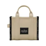 Cartera tipo tote bag de Marc Jacobs, modelo The Small Tote, confeccionada en lona de algodón y poliéster color negro. Presenta el logo de la marca estampado en el frente, asas superiores y correa de hombro ajustable y extraíble.