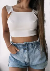 Short de jean celeste de tiro alto con cintura fruncida elástica y cierre frontal con dos botones metálicos. Presenta bolsillos delanteros y dobladillos anchos en los bordes.