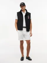 Chaleco negro con cuello chimenea, cierre de cremallera oculto con botones a presión y dos bolsillos laterales ribeteados. Presenta logos bordados en el pecho de Tommy Hilfiger y Cadillac Formula 1 Team.