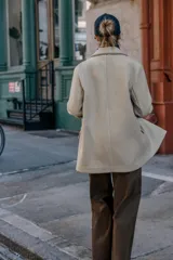 Blazer de corte recto y diseño minimalista, confeccionado en tejido de paño suave color beige. Presenta cuello con solapas clásicas, cierre frontal con un solo botón y dos bolsillos delanteros con solapa.