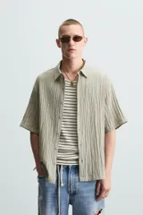 Camisa de manga corta con cuello solapa, confeccionada en tejido de mezcla de lyocell con textura de efecto arrugado y cierre frontal de botones.