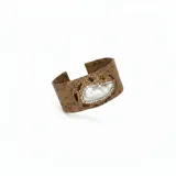 Pulsera rígida tipo brazalete confeccionada en piel con textura de reptil, decorada con una perla barroca central rodeada de incrustaciones de strass en tonos tierra.