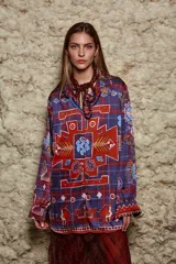 Camisa holgada con estampado geométrico en tonos azules, rojos y marrones. Tiene cuello solapa, mangas largas y cierre abotonado.