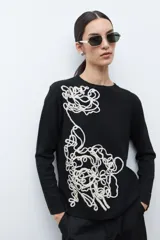 Sweater de punto color rojo melange, con cuello redondo, manga larga y detalle de bordado floral en relieve en color crudo en el frente.