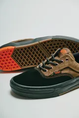 Championes Vans modelo Skate Era Wafflecup, con diseño bicolor en negro y marrón. Presentan una silueta clásica de skate con suela WaffleCup que combina durabilidad y flexibilidad, cordones negros y detalles en color naranja en la lengüeta, plantilla y suela.