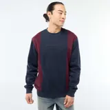 Buzo de cuello redondo con diseño color block en azul marino y bordó. Presenta un estampado minimalista en el pecho y puños acanalados.