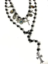 Set de dos collares estilo rosario con cuentas de vidrio esmaltadas en color negro mate y cadena de acero quirúrgico. Incluye múltiples dijes religiosos, cruces y medallas en aleación metálica plateada.