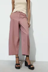 Pantalón de tiro alto con diseño tipo ballon, bolsillos laterales ocultos en costura y cierre frontal con cremallera y botón.