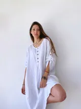 Vestido blanco de lino, corte holgado, con cuello redondo, mangas 3/4 con botones y cierre frontal parcial con botones de madera.