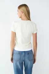 Remera de manga corta color beige, con cuello redondo y detalle de doble capa en el bajo y en las mangas. Confeccionada en tejido de punto single jersey, de corte regular.