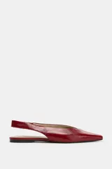 Zapato plano destalonado en piel de color rojo, con diseño de punta fina y detalle de costura central en la parte delantera. Cuenta con tira trasera y suela baja.