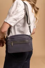 Bandolera de diseño moderno y funcional, confeccionada en nylon color marrón claro. Cuenta con múltiples compartimentos con cierre metálico, herrajes plateados y una correa ancha ajustable con detalle de marca.