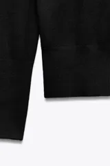 Jersey de punto liso con cuello redondo y manga larga. Presenta detalle de botones decorativos en los puños.