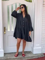 Vestido amplio de lino color verde lima, con cuello mao y abertura frontal con botones de coco. Presenta un diseño con canesú fruncido y volados en los puños de las mangas largas.