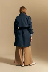 Trench azul marino de corte clásico con cuello amplio, botones frontales grandes en color beige, y detalles en los hombros.