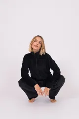 Conjunto de dos piezas confeccionado en tela plush, compuesto por una campera con cierre frontal y cuello alto, y un pantalón de corte recto. Presenta un diseño minimalista y cómodo en color gris claro.