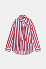 Camisa de manga larga con cuello subido y detalle de lazada frontal. Presenta un diseño de rayas verticales en tonos verde y celeste, con cierre frontal de botones y puños clásicos.