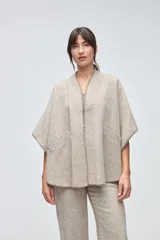 Ruana corta de lana fina sin teñir, con bolsillos laterales y terminaciones tejidas a crochet hechas a mano.