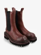 Bota de cuero premium color negro, de diseño minimalista estilo Chelsea con elásticos laterales y tiradores superiores. Posee una suela track de goma con plataforma y taco cuadrado con detalle de madera.