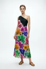 Vestido midi asimétrico de un solo hombro, con estampado floral pictórico en tonos vibrantes sobre fondo negro.
