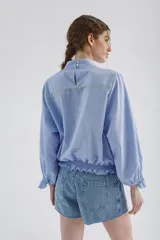 Blusa lila de cuello alto y manga 3/4 con elástico en el bajo. Presenta volados verticales en el frente.