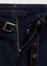 Pantalón de jean estilo wideleg color azul oscuro, con tiro medio, cuatro bolsillos y cinturón incorporado con hebilla metálica.