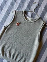 Pin de gancho metálico con dije rectangular bordado que presenta un corazón rojo central atravesado por espadas, decorado con cuentas rojas y doradas en el borde.