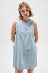 Vestido corto de jean blanco con tirantes anchos, cuello redondo, corte holgado y bolsillos laterales.