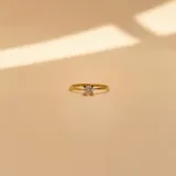 Anillo solitario de oro amarillo 18k con piedra central de circonia engarzada en cuatro puntas, acompañado por una alianza lisa de oro a juego.