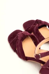 Sandalia de tacón cuadrado medio, confeccionada en terciopelo negro. Presenta un diseño de tiras cruzadas con nudo en la parte delantera y una tira ajustable con hebilla en el tobillo.