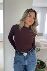 Body de manga larga en color marrón, confeccionado en tejido acanalado con cuello alto. Presenta un ajuste al cuerpo y cierre inferior.